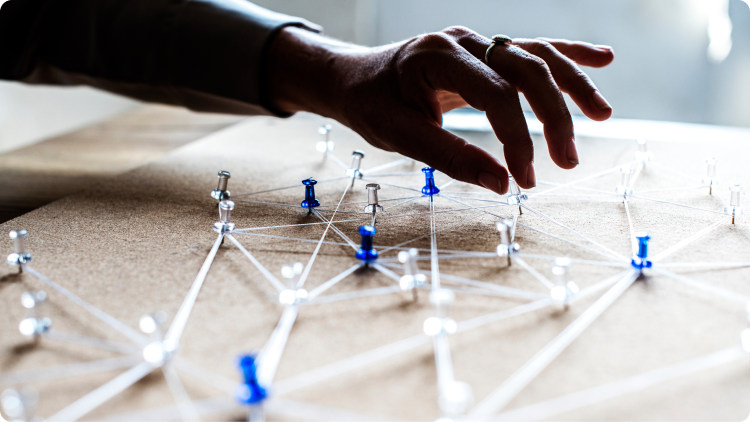  A hand gently touches a network of pins, creating a tactile connection between the person and the intricate structure