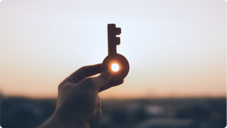 Key held up by individual with sun setting behind
