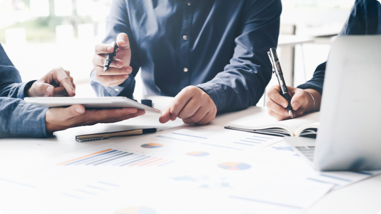 Grup de trei persoane care colaboreazÄ la o masÄ cu un laptop Èi pagini