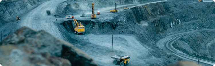 Um grande poÃ§o a cÃ©u aberto cheio de equipamento de construÃ§Ã£o, mostrando maquinaria pesada e um ambiente de estaleiro expansivo