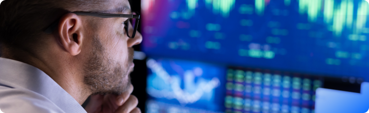 Um homem de Ã³culos observa atentamente um ecrÃ£ que apresenta dados e tendÃªncias do mercado bolsista