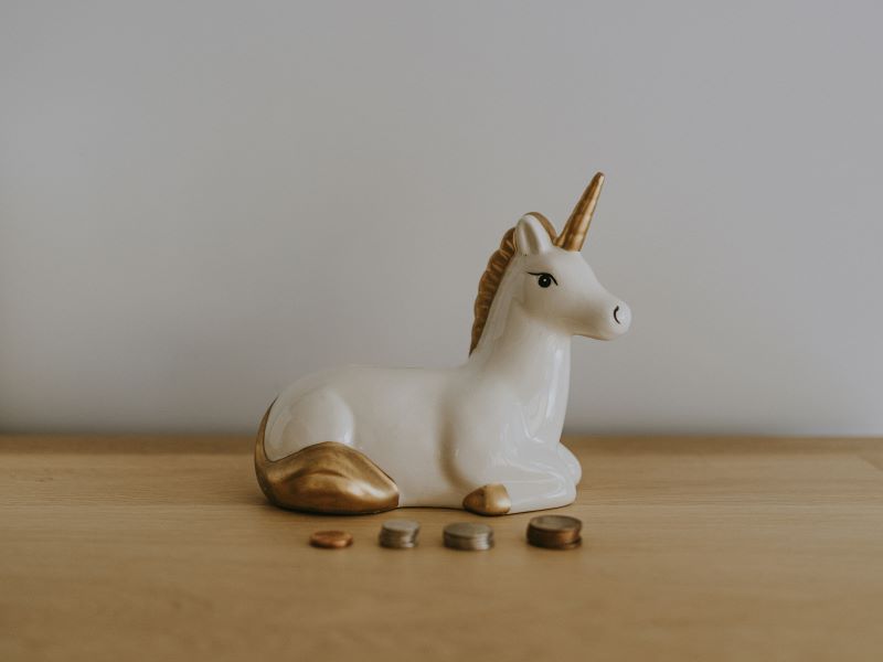Imagen de una figura de unicornio rodeada de monedas en un articulo sobre quÃ© es un colchÃ³n financiero