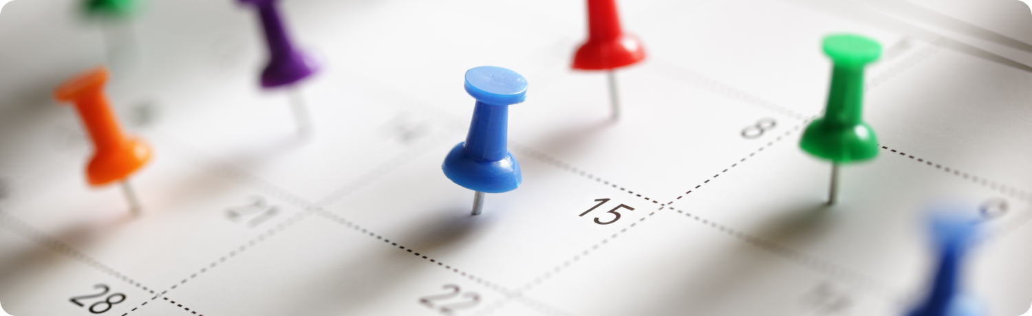  A wall calendar marked with colorful pins indicating important dates and events throughout the month