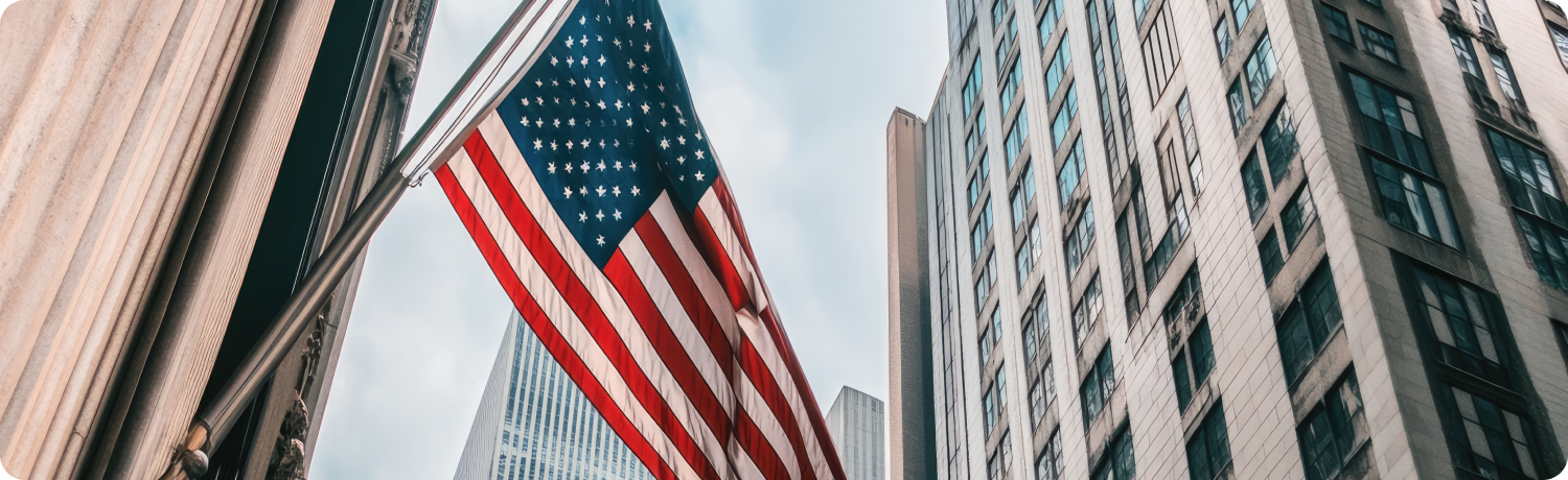 Un steag american fluturÄ Ã®n faÈa unor zgÃ¢rie-nori, simbolizÃ¢nd patriotismul Ã®n mijlocul arhitecturii urbane