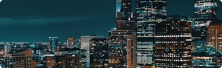 A nighttime cityscape featuring tall buildings illuminated against a dark sky