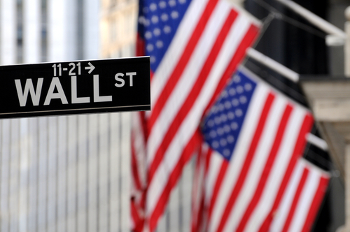 placa de la calle wall street con la bandera de eeuu en el fondo
