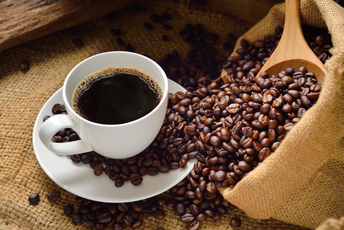 una taza de cafe y granos de cafe al lado