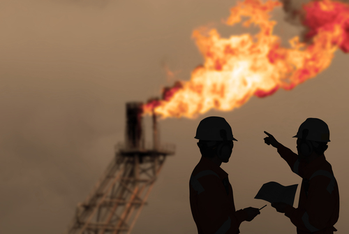 Dos hombres conversando con plataforma de petroleo al fondo