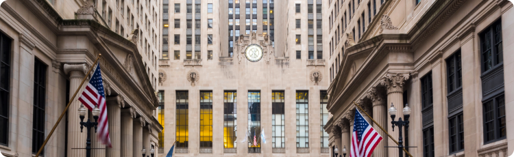 Vue grand angle du bÃ¢timent du Chicago Board of Trade avec des drapeaux amÃ©ricains et une architecture classique, reprÃ©sentant le centre historique du commerce des matiÃ¨res premiÃ¨res et de la spÃ©culation financiÃ¨re aux Ãtats-Unis