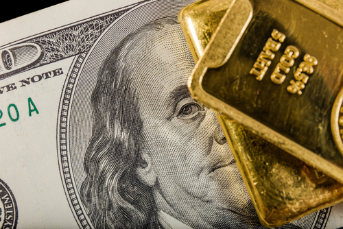 Una nota de dolar y un barra de oro juntas