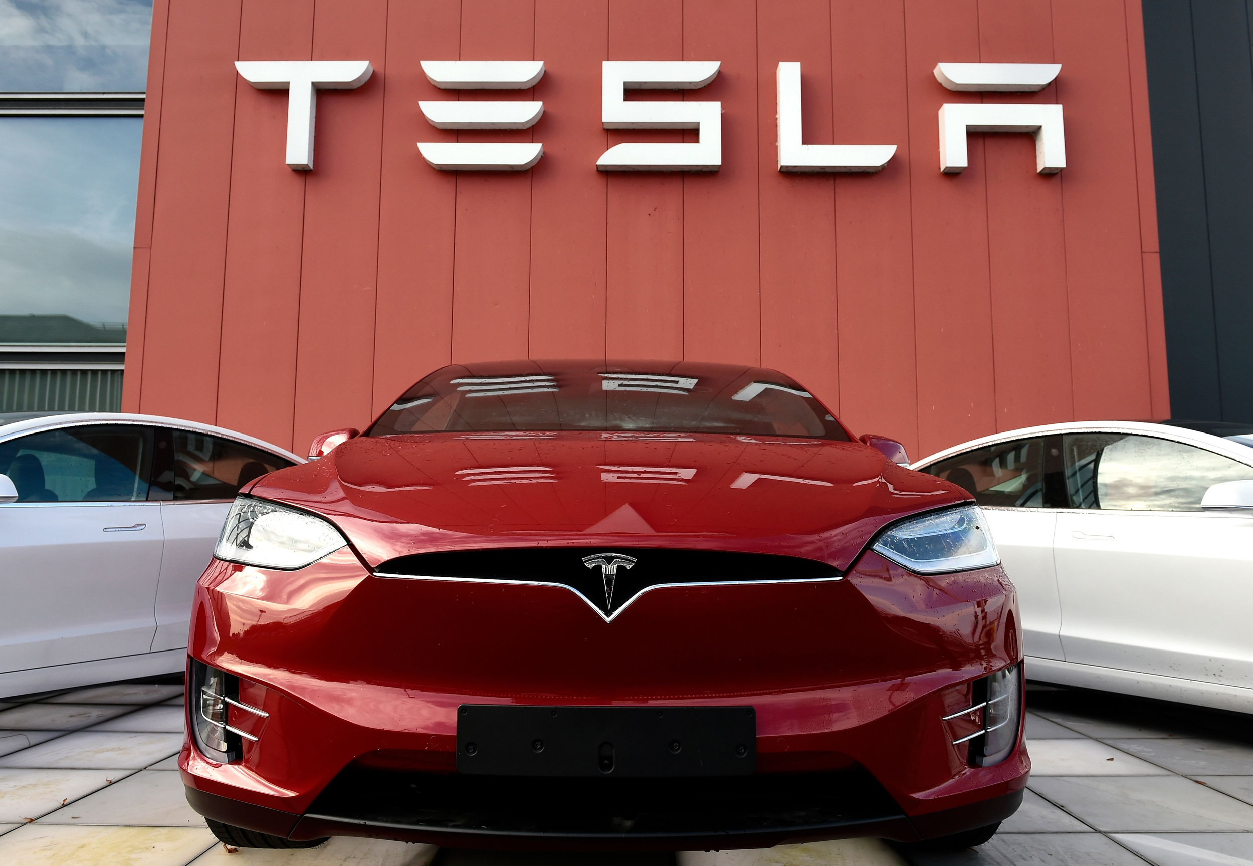 Un auto tesla frente al logo de tesla