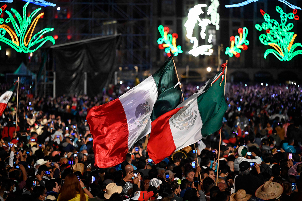 Dos banderas de mexico en medio al publico en la comemoracion de las fiestas patrias de mexico