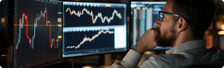 Seorang pria mengenakan setelan jas sedang memeriksa grafik pasar saham di layar, fokus pada analisis data keuangan