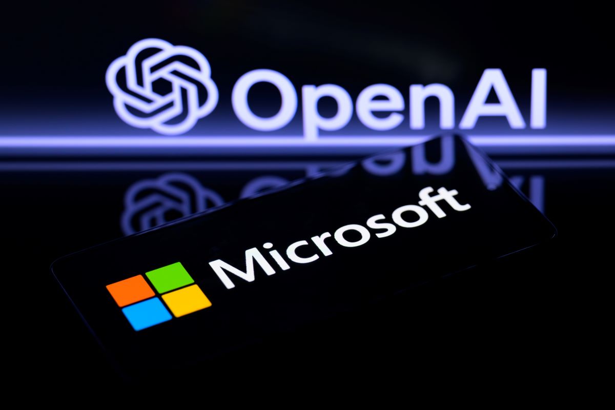 Un telefono con el logo de microsoft con el logo de open ai en una pantalla al fondo