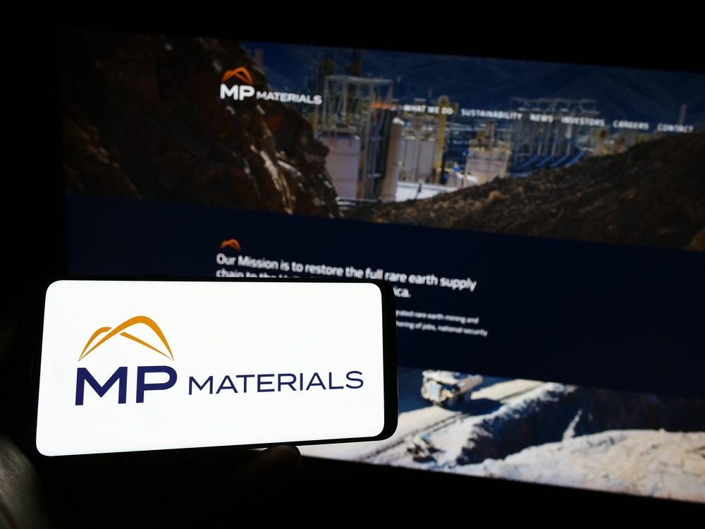 Persona que sostiene un smartphone con el logotipo de MP Materials