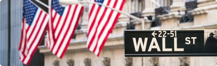 Sinal de rua de Wall Street com bandeiras americanas, simbolizando os mercados financeiros dos EUA e o centro de negociaÃ§Ã£o de aÃ§Ãµes.