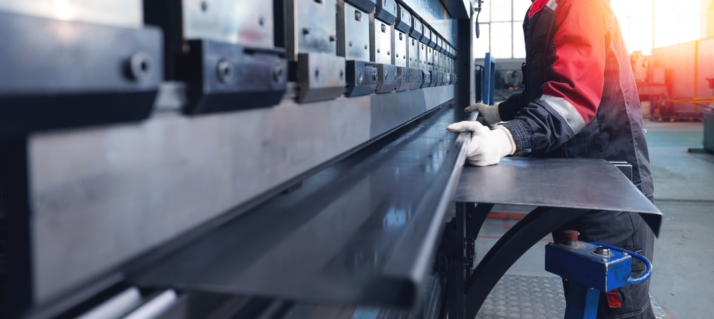 Trabajador masculino operando una prensa plegadora industrial de metal en un entorno de fÃ¡brica, pancarta.