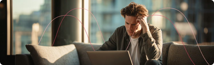 Jovem sentado num sofÃ¡ a analisar dados financeiros num computador portÃ¡til, simbolizando o stress e a incerteza no investimento durante perÃ­odos de abrandamento econÃ³mico.