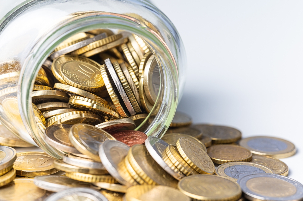 Tarro de cristal volteado al reves, con monedas derramandose.