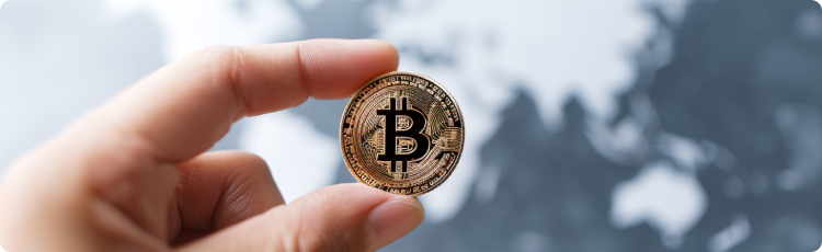 DÅoÅ trzymajÄca monetÄ Bitcoin na rozmytym tle mapy Åwiata, ilustrujÄca globalnÄ adopcjÄ kryptowalut i miÄdzynarodowe rynki aktywÃ³w cyfrowych.