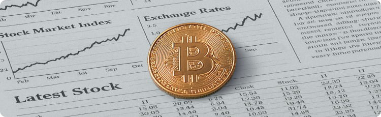 Bitcoin fÃsico sobre un periódico financiero que muestra los Ãndices bursátiles y los tipos de cambio.