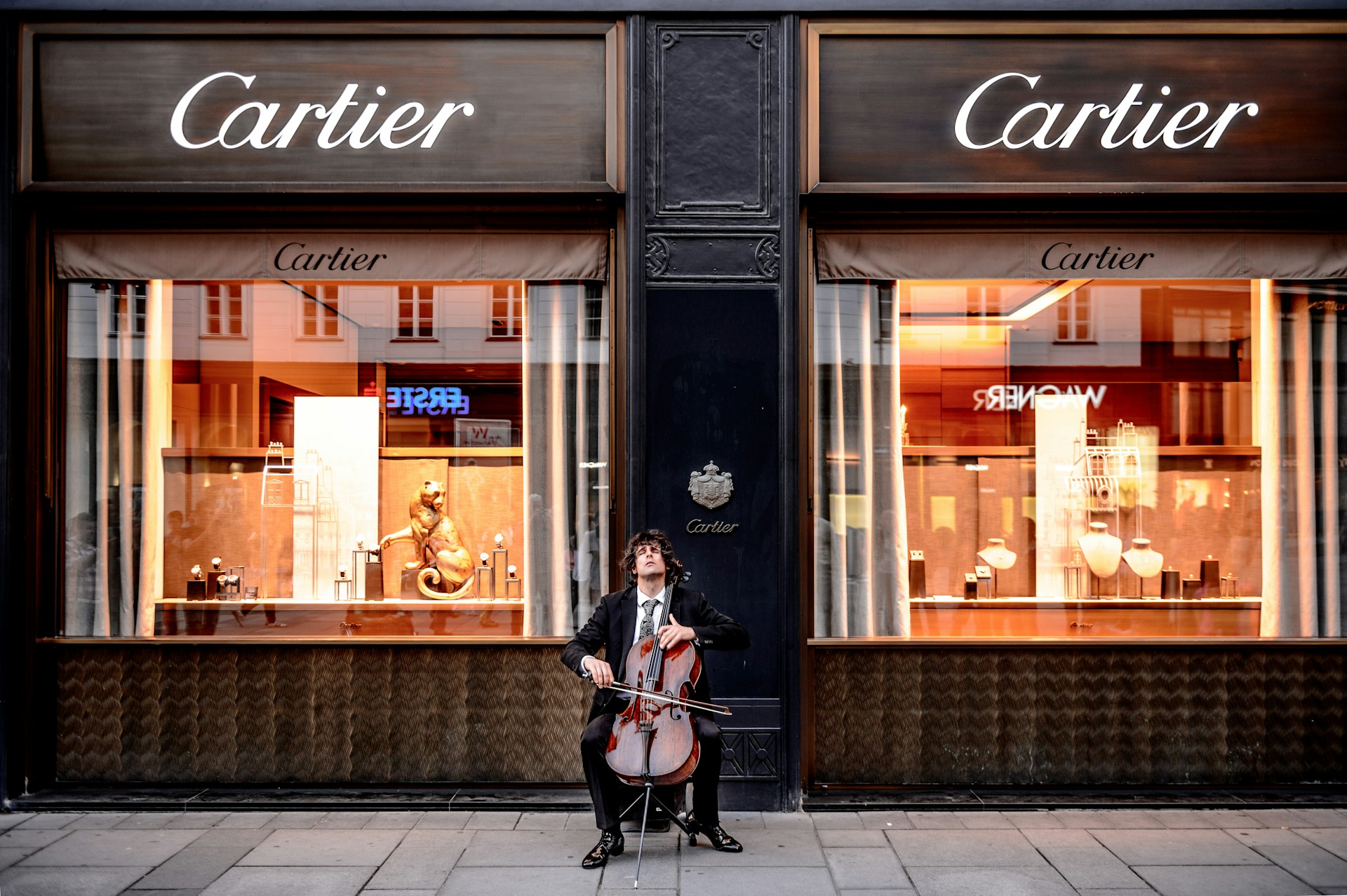 Homem tocando violoncelo na frente da loja de artigos de luxo Cartier