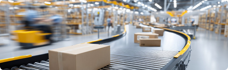 Sistema moderno de correias transportadoras de armazÃ©m a transportar caixas de cartÃ£o, com fundo desfocado a mostrar prateleiras e trabalhadores em movimento