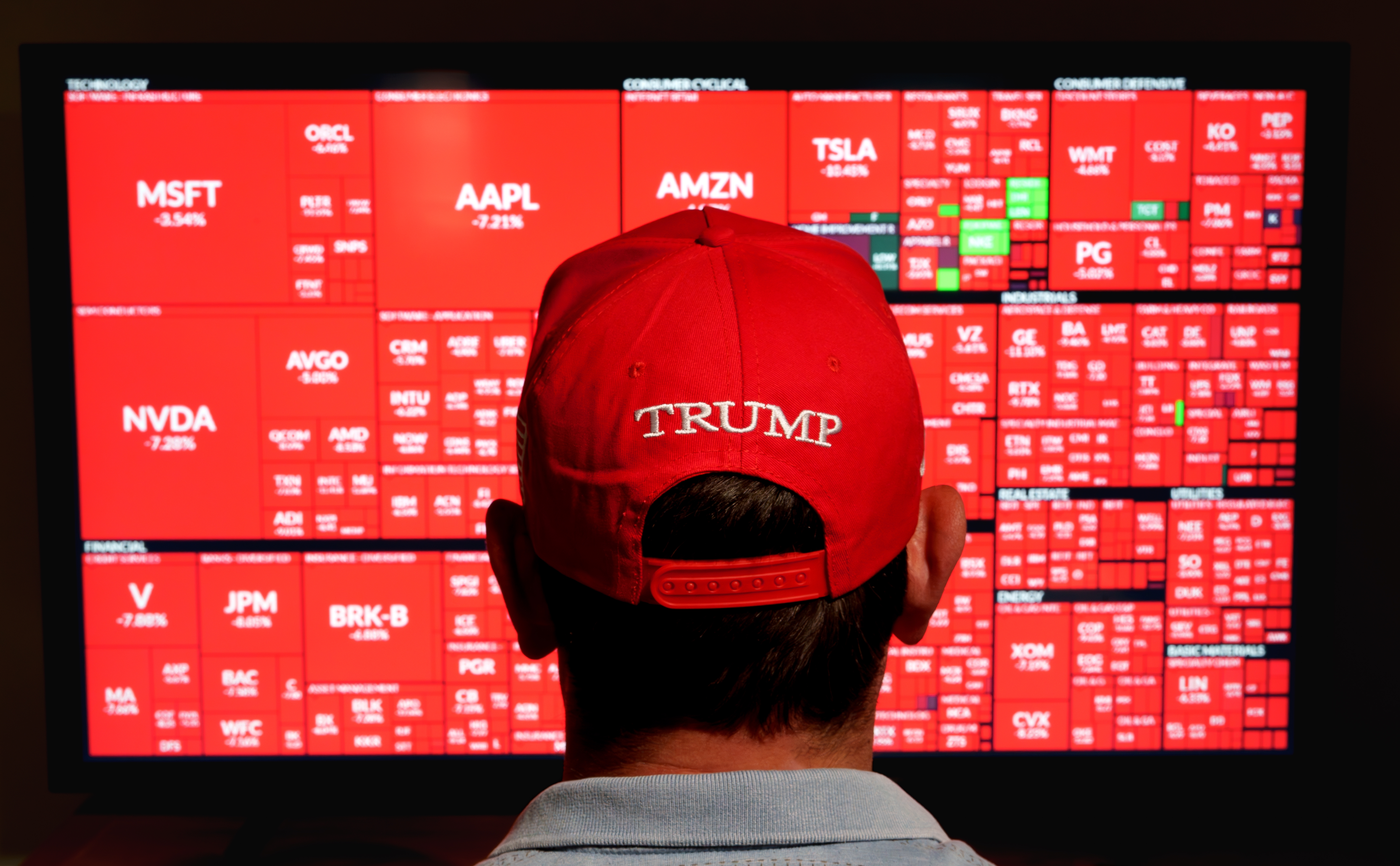 Hombre con sombrero rojo de Trump observando el mapa de calor del mercado de valores con graves pÃ©rdidas en el sector S y P 500 cuando Trump introdujo aranceles. Stafford, Reino Unido, 18 de mayo de 2025.