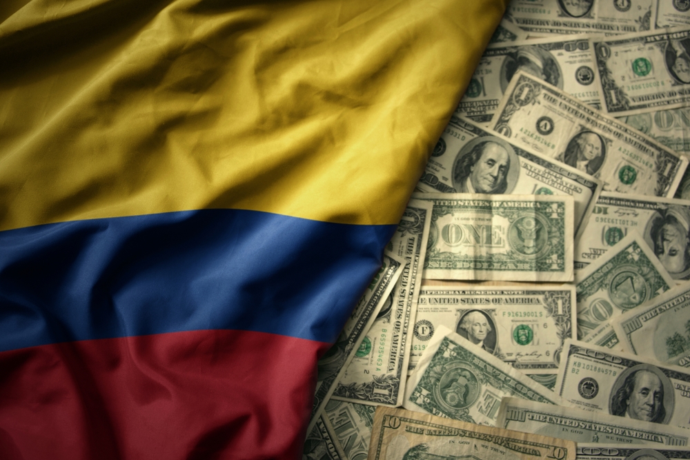 gran colorido ondeando la bandera nacional de colombia sobre un fondo de dinero americano. concepto de finanzas