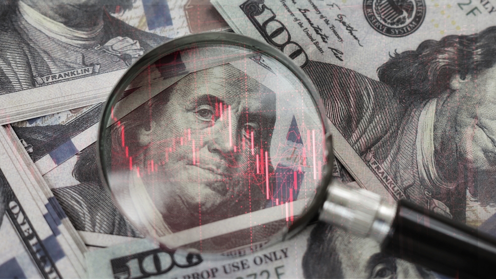 Una flecha roja hacia abajo dentro de una lupa colocada sobre un billete