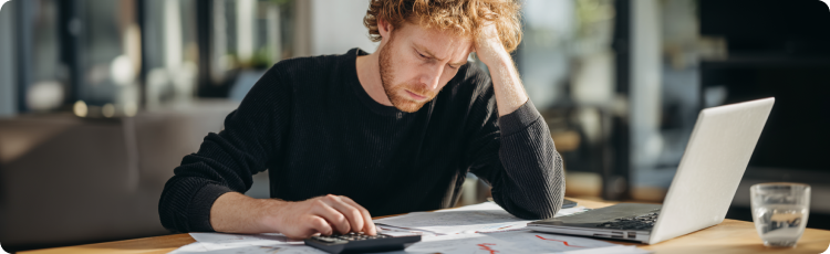 Stresszes befektetÅ, aki pÃ©nzÃ¼gyi dokumentumokat elemez szÃ¡molÃ³gÃ©ppel Ã©s laptoppal, befektetÃ©si vesztesÃ©gein vagy portfÃ³liÃ³kockÃ¡zat-kezelÃ©si kihÃ­vÃ¡sain elmÃ©lkedik.