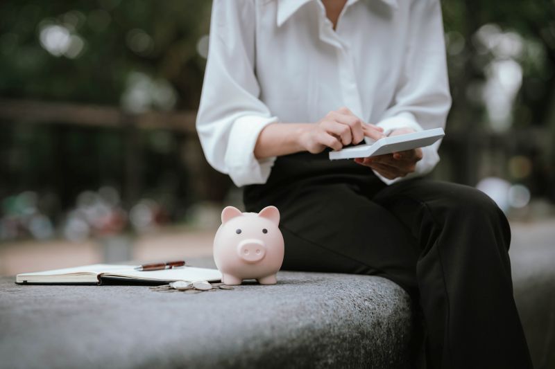 Imagen de una persona con una calculadora y una hucha en un artÃ­culo sobre cÃ³mo invertir con poco dinero