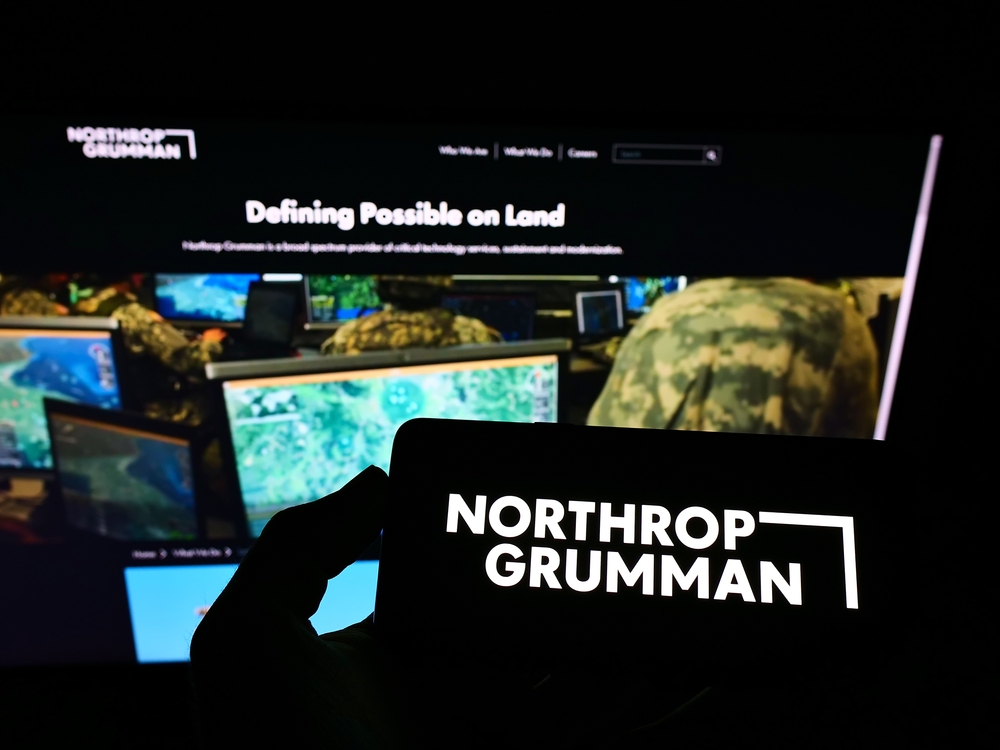 Persona que sostiene un telÃ©fono mÃ³vil con el logo de la empresa de defensa estadounidense Northrop Grumman Corporation en pantalla frente a la pÃ¡gina web