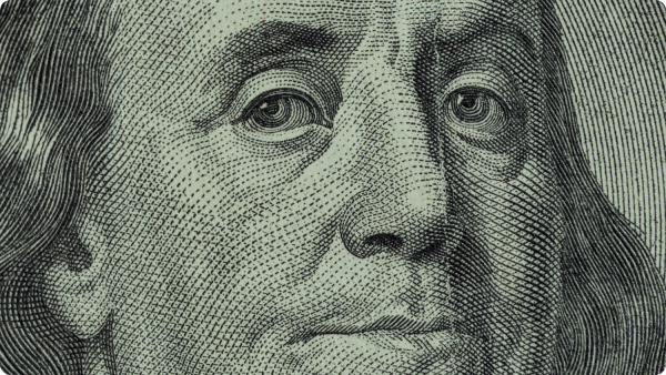 Detailed view of Benjamin Franklin's face featured on a one hundred dollar bill, highlighting the artistry of currency design