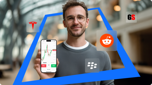 Un homme montre un smartphone avec l’interface de l’application XTB qui illustre des tendances de marché et des cours des actions