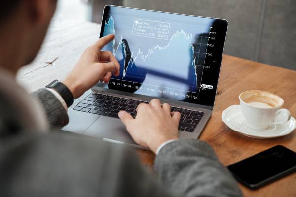 analiza pe laptop cu un grafic financiar si o ceasca de cafea pe birou