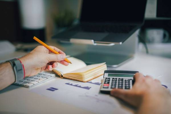 Imagen de una persona frente a una calculadora en un artículo sobre qué son los planes de ahorro