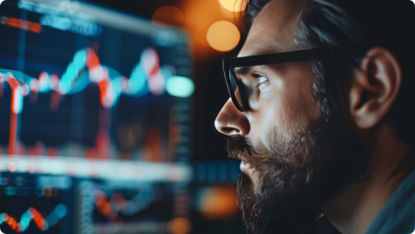 Một người đàn ông chăm chú theo dõi biểu đồ chứng khoán trên màn hình