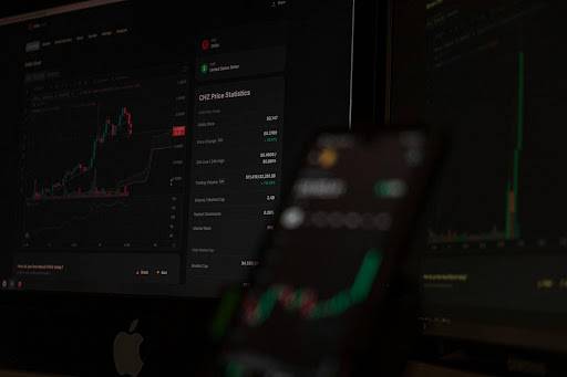 Ecrãs de computador e smartphone a mostrar gráficos de negociação forex em tempo real
