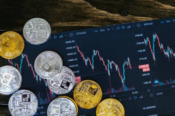 Imagem com gráfico de investimentos e moedas digitais a representar criptomoedas