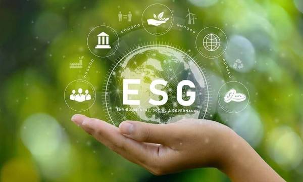 Mão de criança a segurar o planeta terra escrito ESG em fundo verde