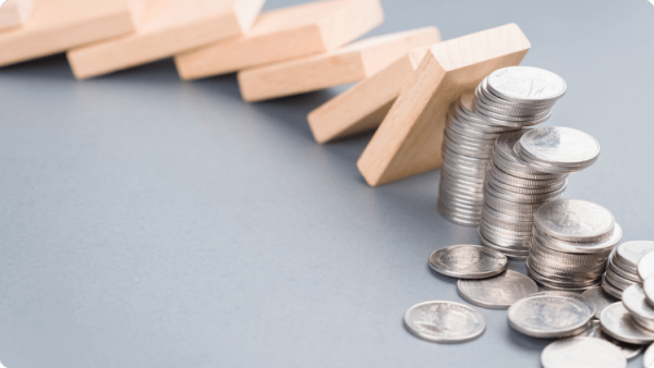 โดมิโนล้มกระทบกองเหรียญ สื่อถึงปัญหาทางธุรกิจและผลกระทบทางการเงิน