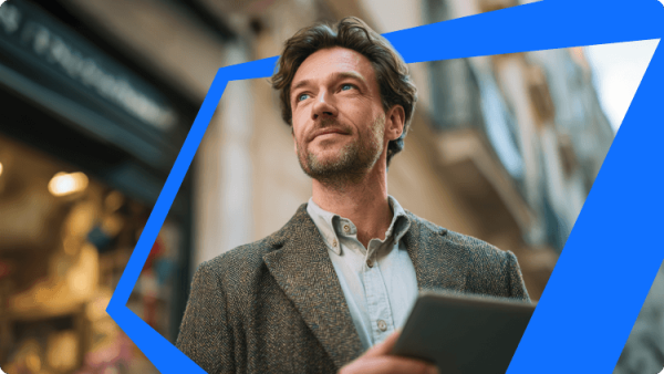 Pria percaya diri memegang tablet sambil berjalan di area perkotaan, melambangkan investor independen yang menjelajahi peluang di saham BDC dan investasi kredit.