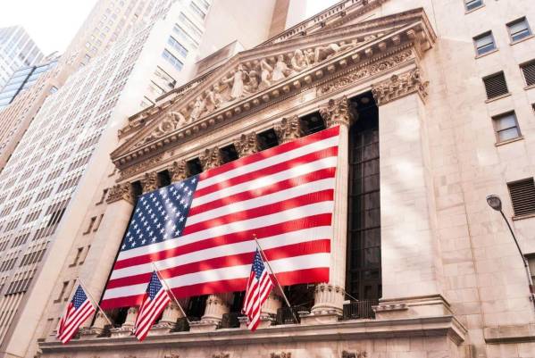 Bandeiras dos Estados Unidos hasteadas em frente a um edifício histórico, a simbolizar a influência da economia americana no desempenho do S&P 500