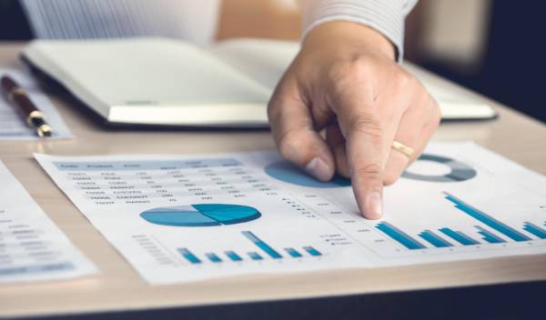 Investor analyzuje finanční grafy a výnosy, symbolizující rozhodování mezi ETF vs. podílovými fondy.