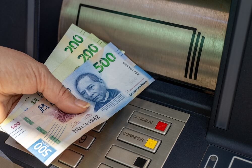 Una mujer retira dinero mexicano de un cajero automÃ¡tico.