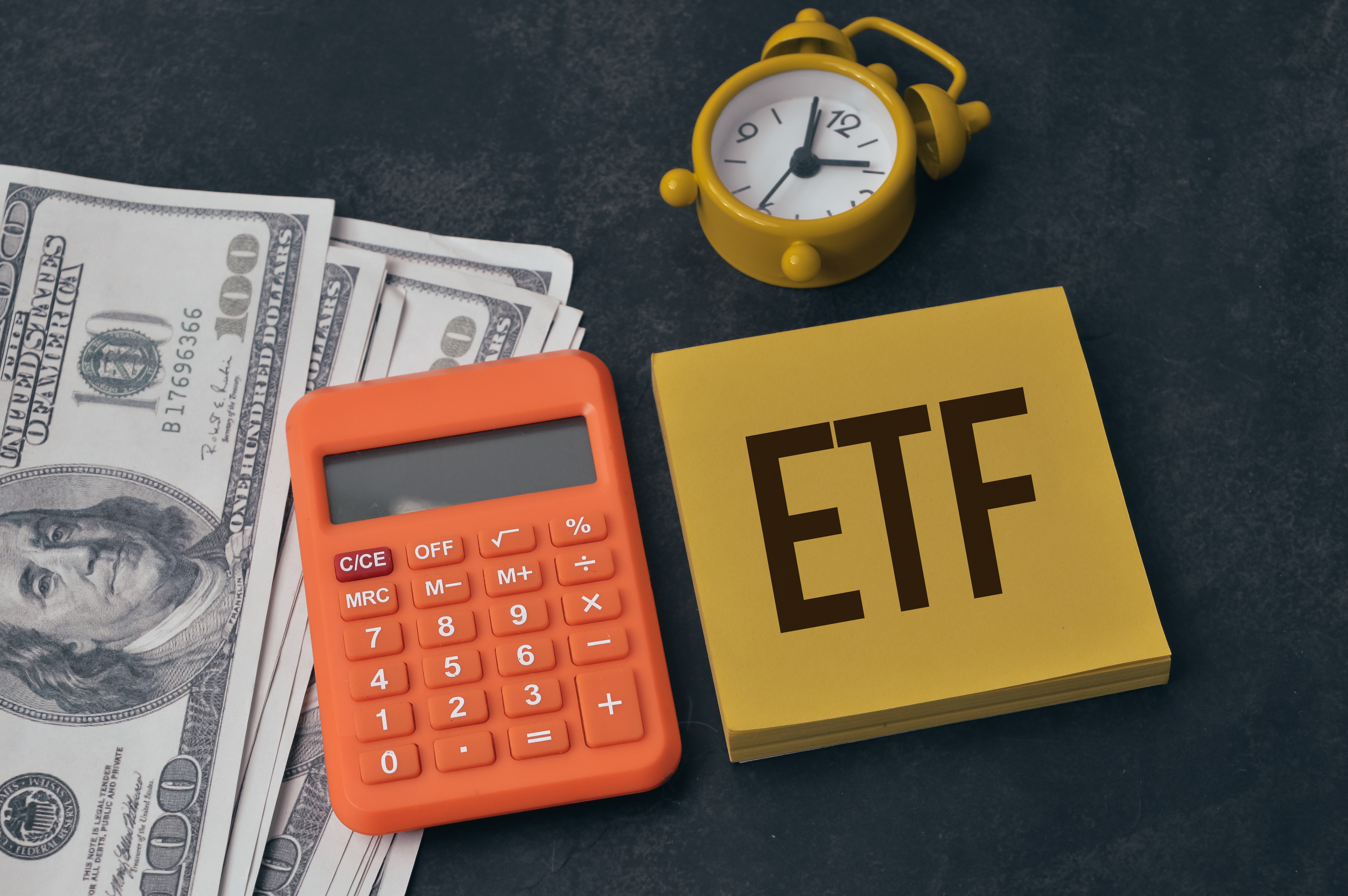 investire in ETF, post-it con scritta ETF, calcolatrice finanziaria e dollari americani