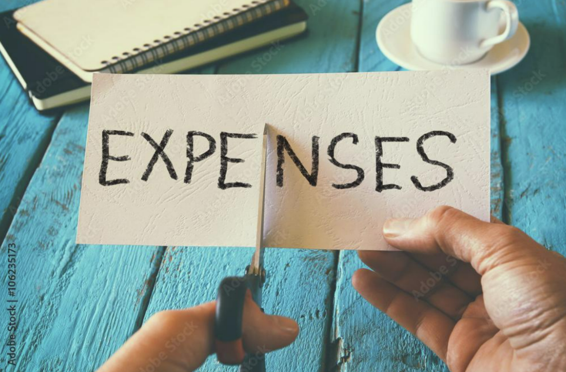 A man hand holding a card with the word expenses - cutting expenses and costs concept