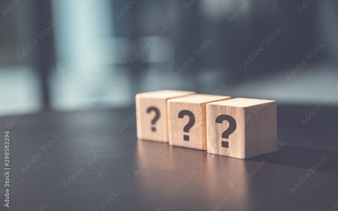 Questions Mark word FAQ in wooden cube block on table background.