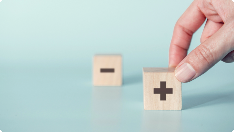 A hand reaching out to touch one of two wooden dice, each marked with plus and minus signs, set against a greenish background.